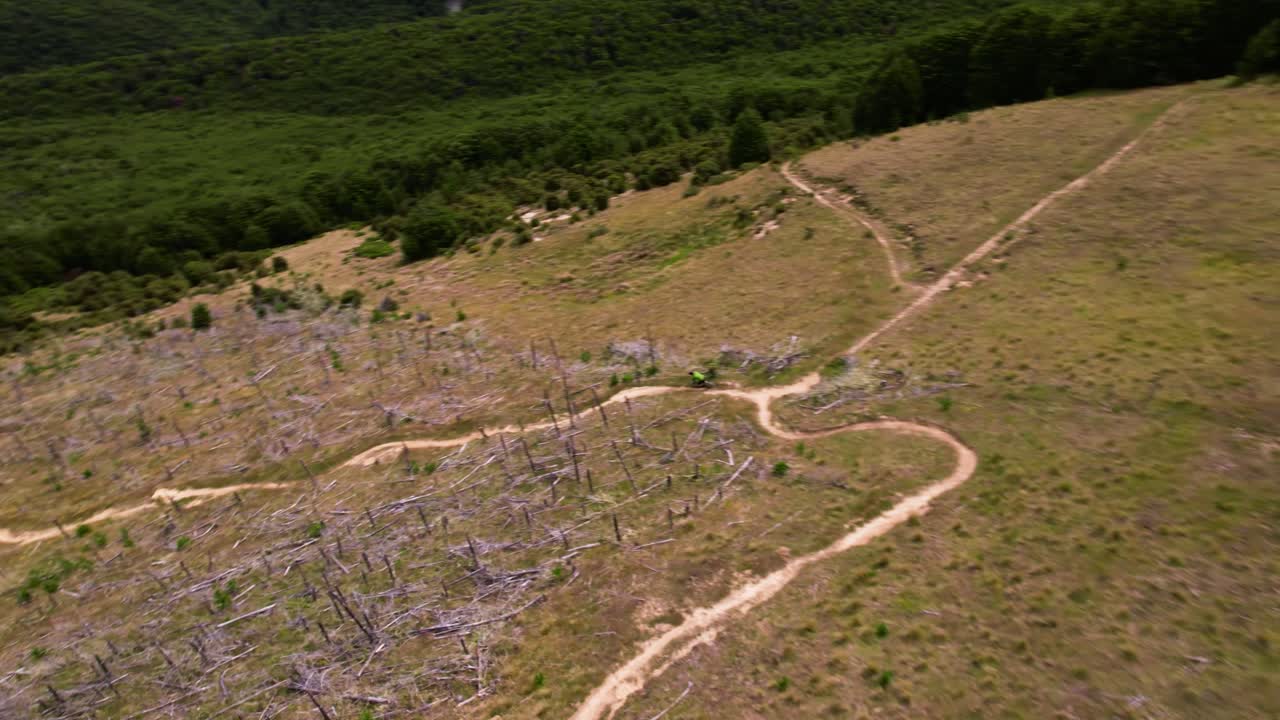 Drone tracking a mountain biker, moving downhill in sunny New Zealand