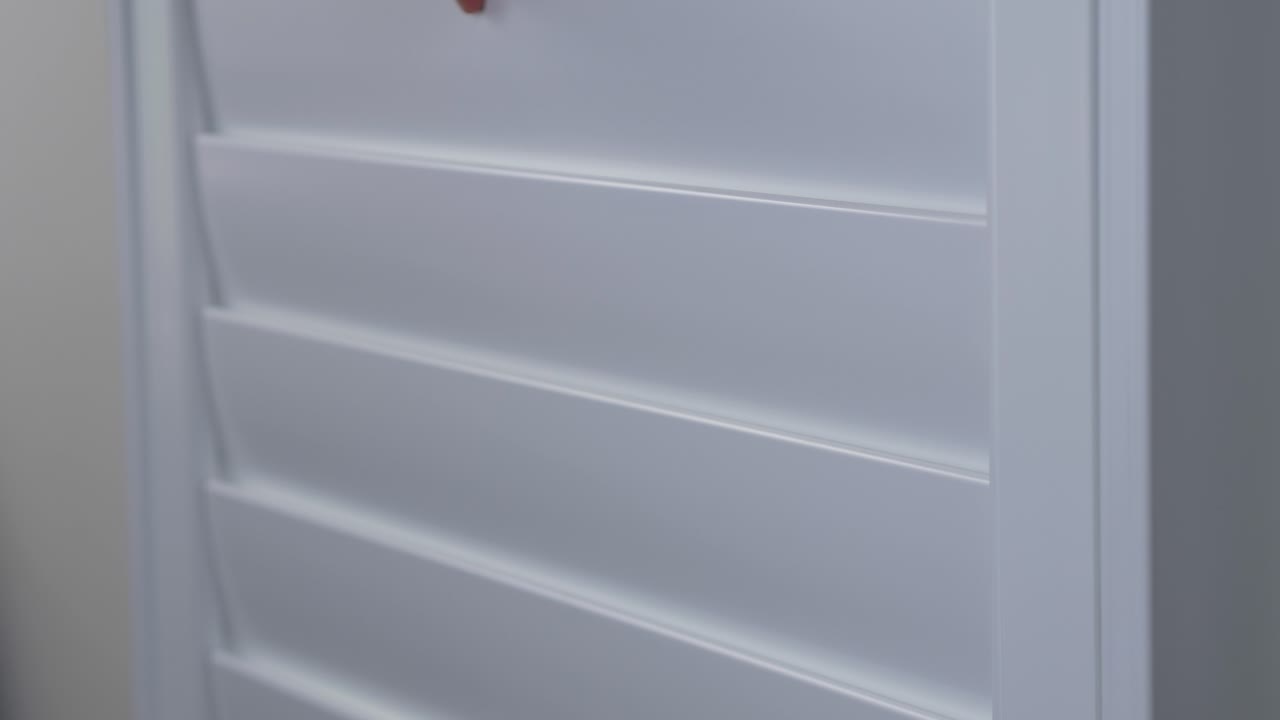Close-up shot of Plantation Shutters window frame slats being closed with hands in house interior design wall kitchen privacy security protection 4K
