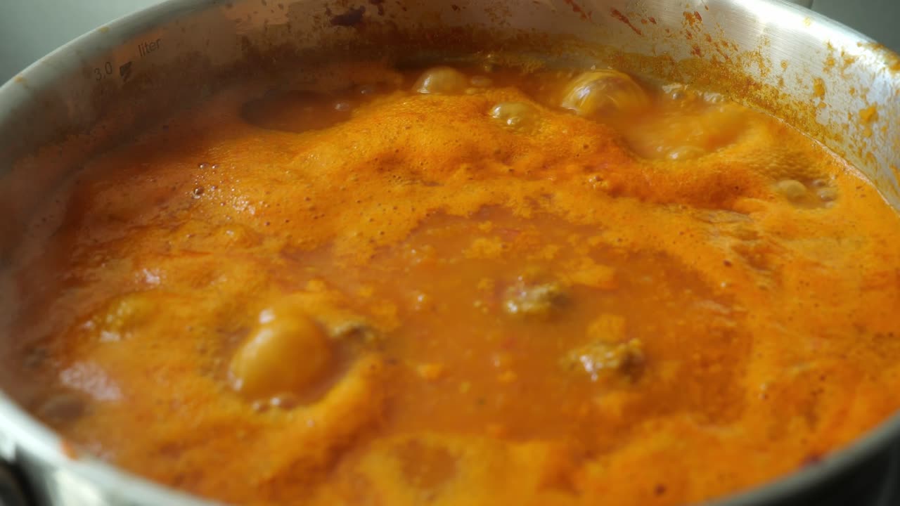 vista de cerca de la sopa de tomate está burbujeando en una sartén