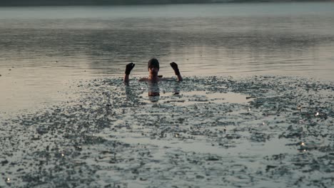 A-young-man-in-a-frozen-lake-jumping-in-the-water-with-high-hands