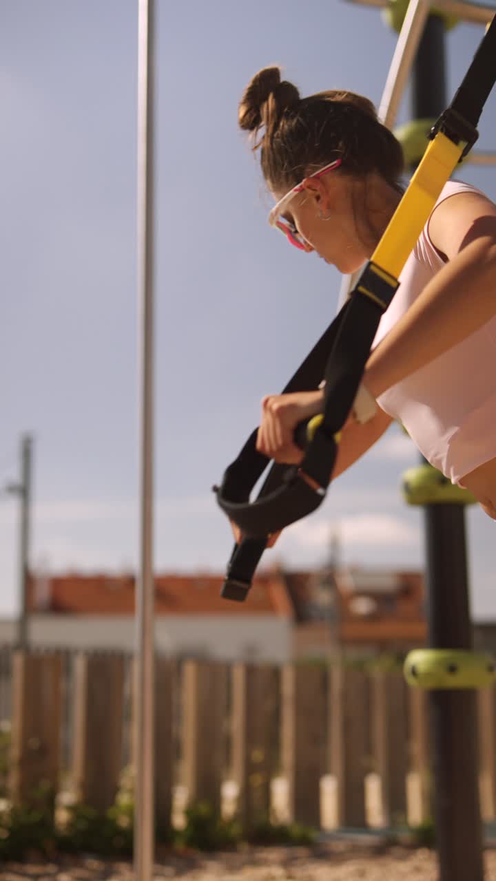 Woman exercising outdoors with TRX straps