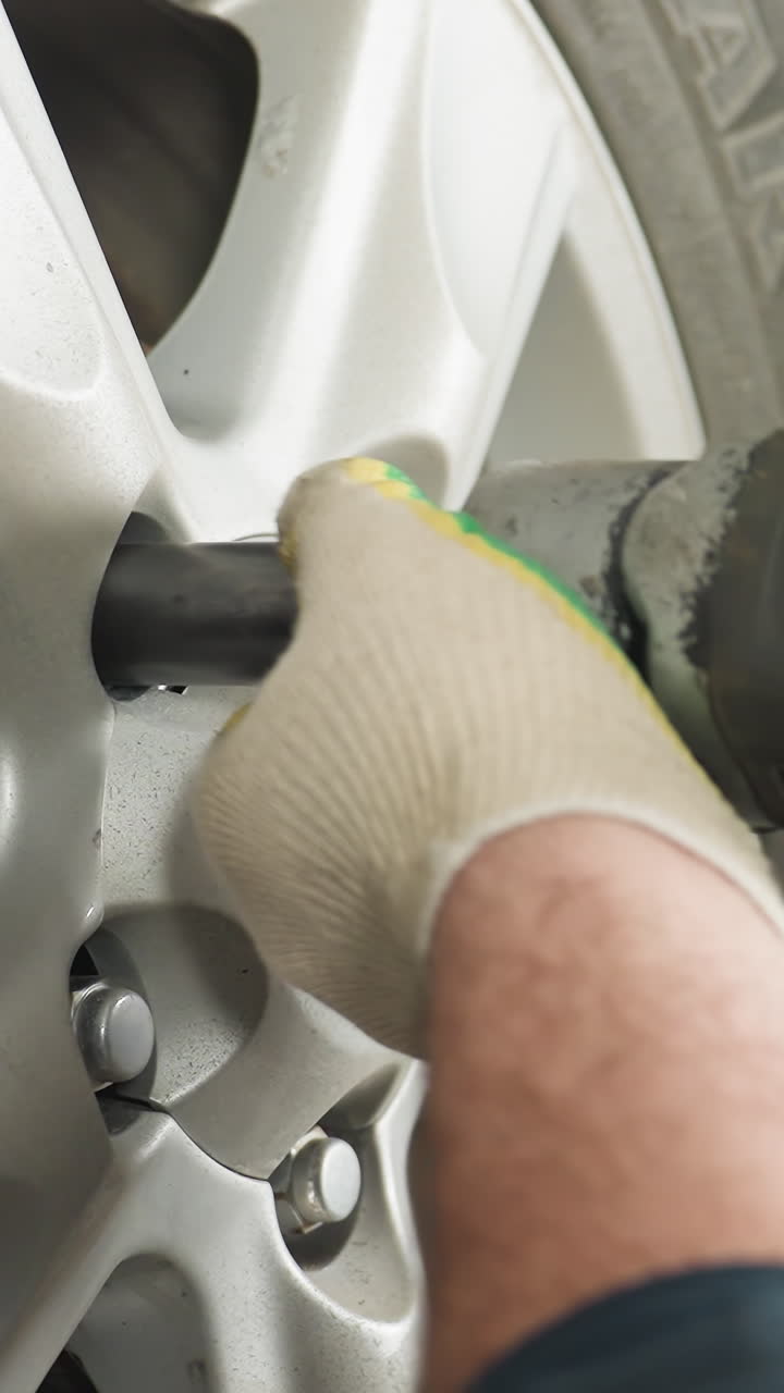 vista de cerca de la cabeza de un mecánico observando a un colega usando una herramienta neumática para apretar los pernos de las ruedas de automóviles en un garaje, el trabajo en equipo y la precisión en la reparación de automóviles aseguran la alineación adecuada de las ruidas