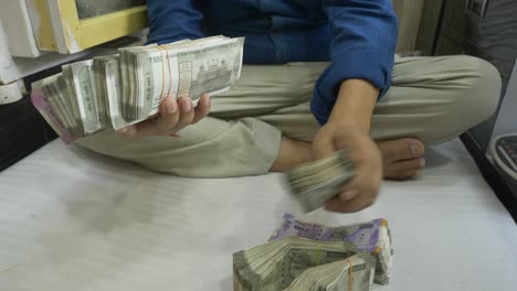 a businessman holding a stack of indian currency, wealth, cash in hand, wide shot