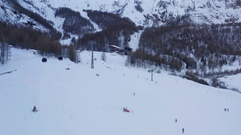 Aerial-of-people-skiing-down-slope-and-cable-cars-on-ski-lifts-at-resorts