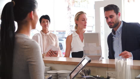 clientes ordenando y pagando en el mostrador de un café