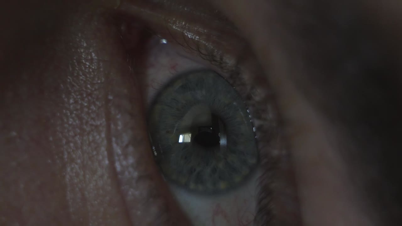 primer plano macro del ojo de un hombre abriéndose, mirando a su alrededor y mirando su teléfono