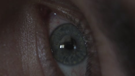 macro close up of a man's eye opening, looking around, and looking at his phone