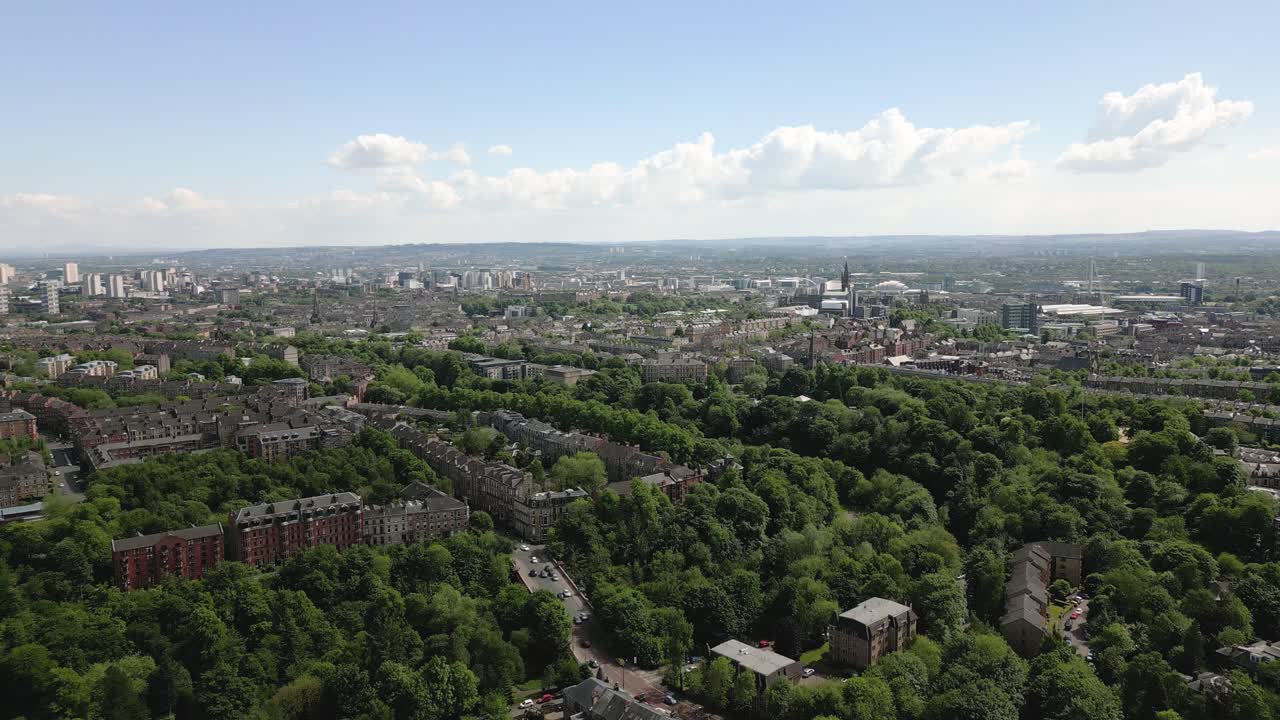 Aerial fly over Glasgow Botanic Gardens with Glasgow West End expansive green parkland and city skyline, Glasgow, Scotland, UK
