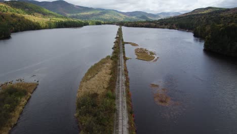 Scenic-fall-aerial-view-of-old-railway-track-between-lakes-and-hills