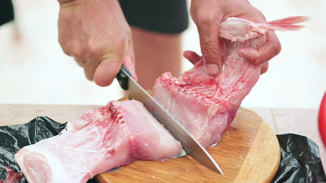 Close up of a man slicing a fish fillet on a wooden cutting board