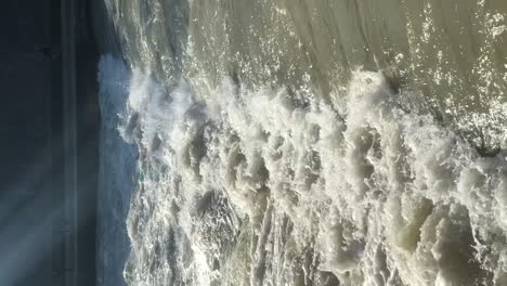 VERTICAL-slow-motion-view-of-powerful-river-water-flowing-down-a-weir-waterfall