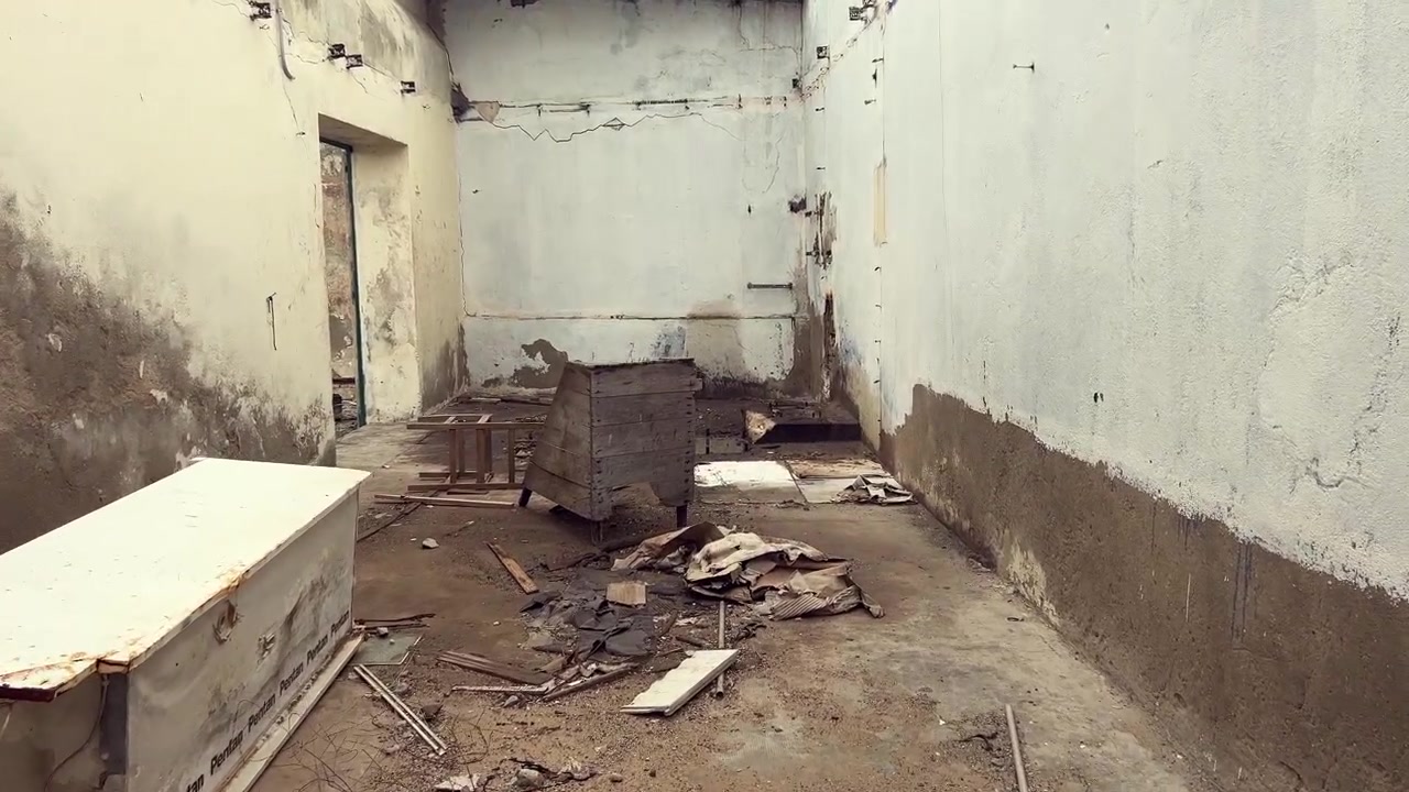 Muri fatiscenti e pittura scrostata incorniciano una stanza desolata piena di detriti edili e resti di occupazione passata, catturando una scena di degrado urbano a Barbate, Andalusia, Spagna.