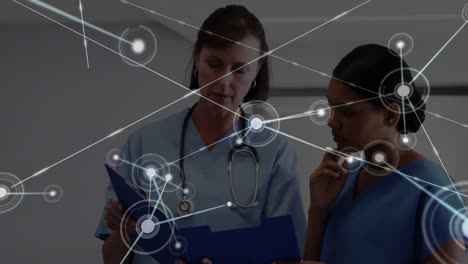 Digital-animation-of-glowing-network-of-connections-against-female-doctor-and-female-medical-profess