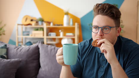 man relaxing at home with tea and cookie