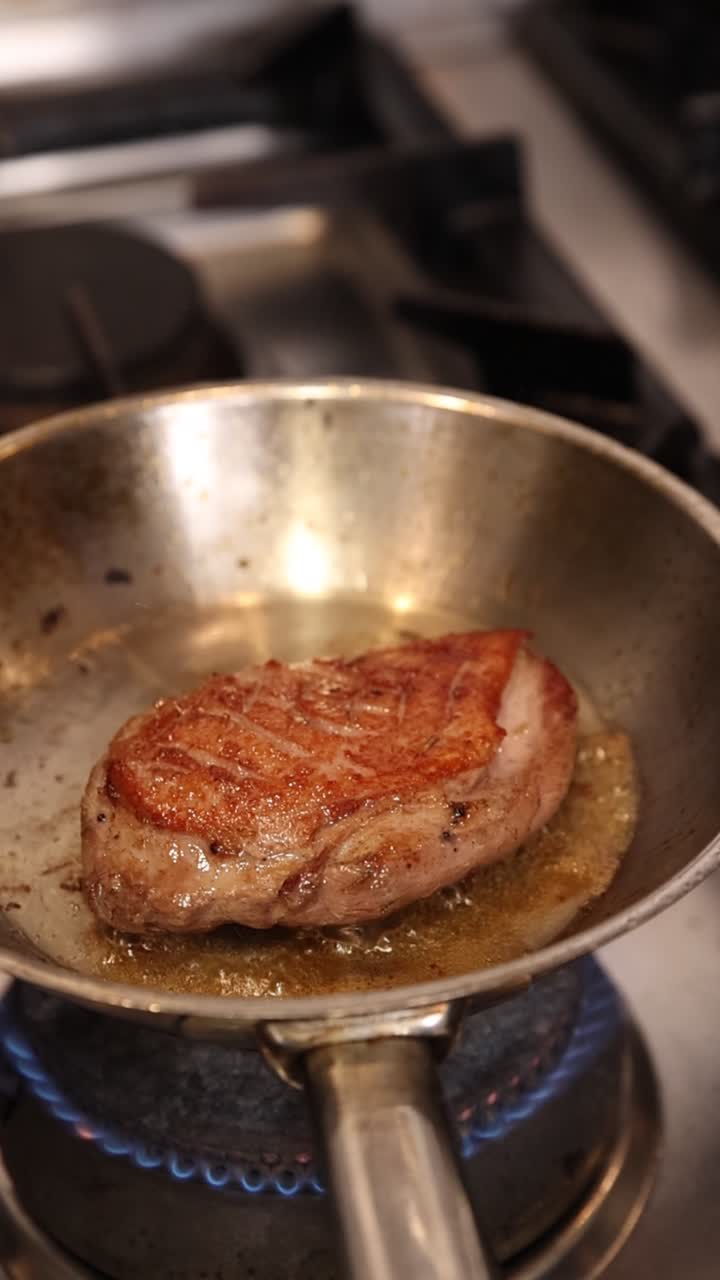 Anatra che sfrigola in una padella su un fornello a gas.