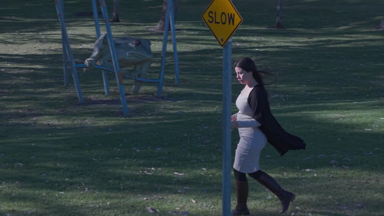 A young Latina woman leisurely walks in a quiet, sunlit park. Captured in warm afternoon light, the scene depicts a peaceful outdoor moment, highlighting solitude and serenity