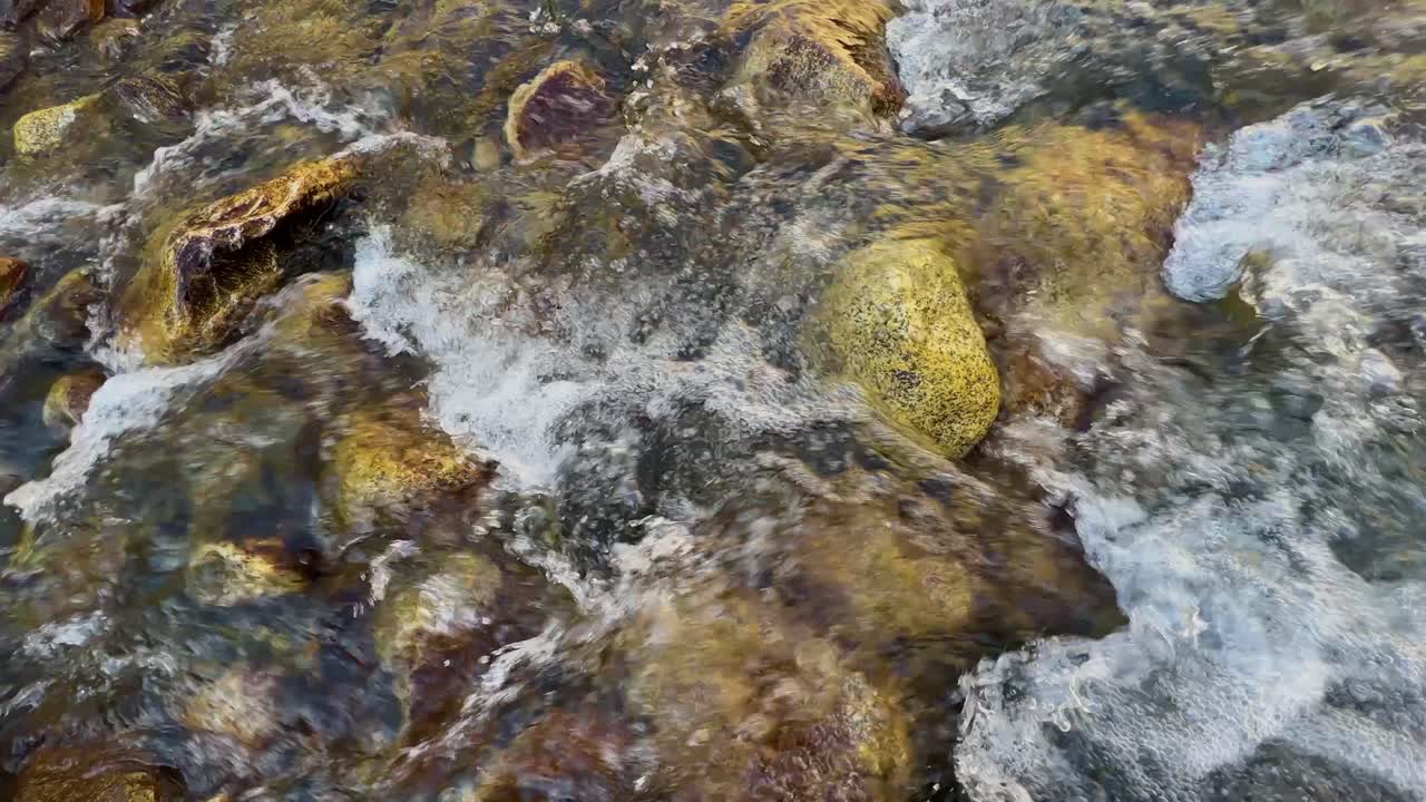 Primo piano dell'acqua di un fiume che scorre colpendo le pietre