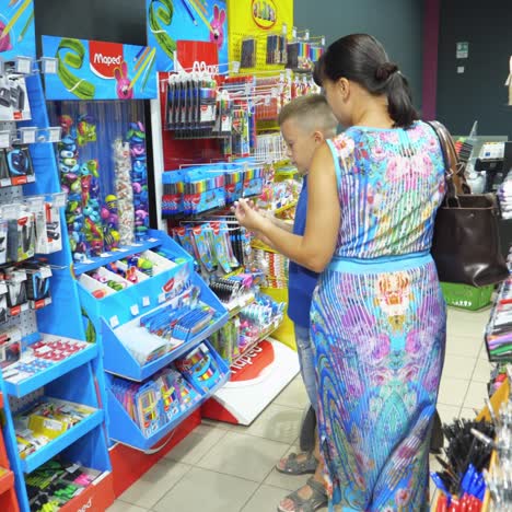 vinnitsa, ukraine - august, 2018: back to school concept. young mother and little boy buying school supplies in store