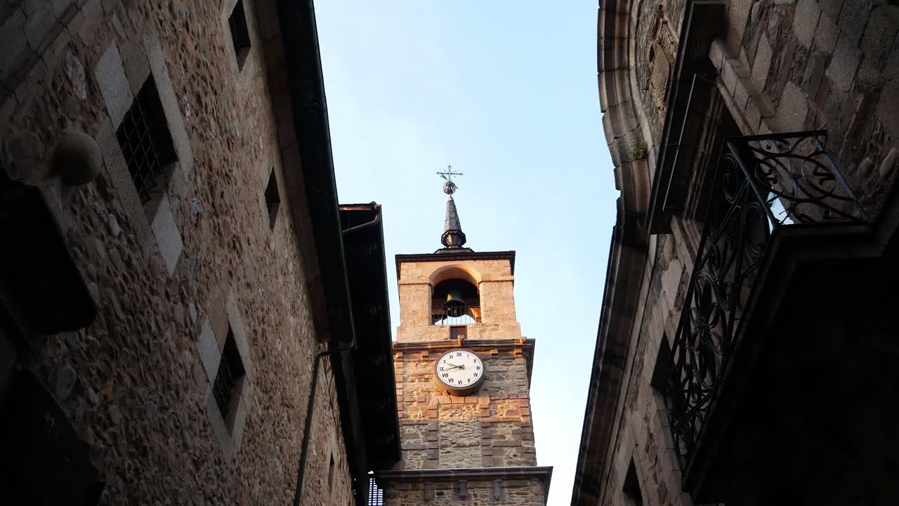 Tilt down over an old bell - clock tower in a stone town
