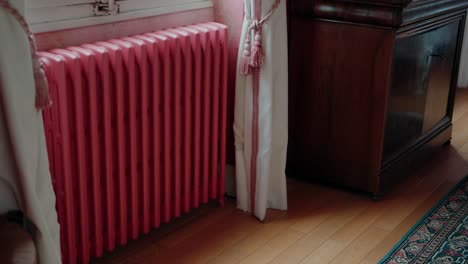 radiador rosa por una ventana con cortina en una habitación acogedora