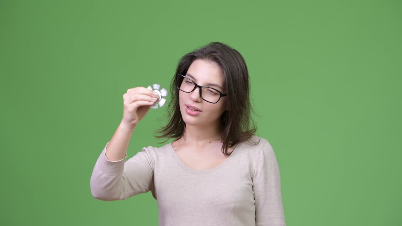 Young beautiful woman playing with fidget spinner and focusing