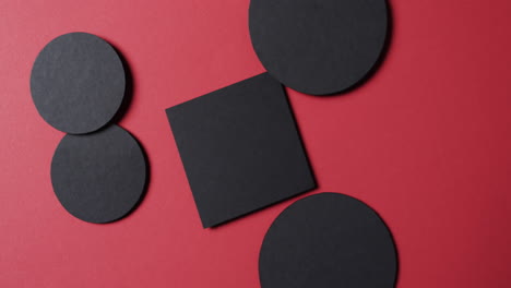 video of close up of square and circles of black paper and copy space on red background