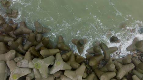 Aerial-establishing-view-of-Port-of-Liepaja-concrete-pier,-Baltic-sea-coastline-,-foggy-day-with-dense-mist,-moody-feeling,-big-storm-waves-splashing,-birdseye-drone-dolly-shot-moving-left