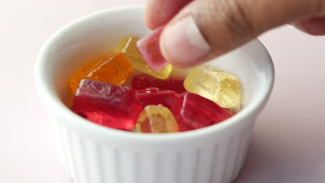 hand picking colorful gummy candies from bowl