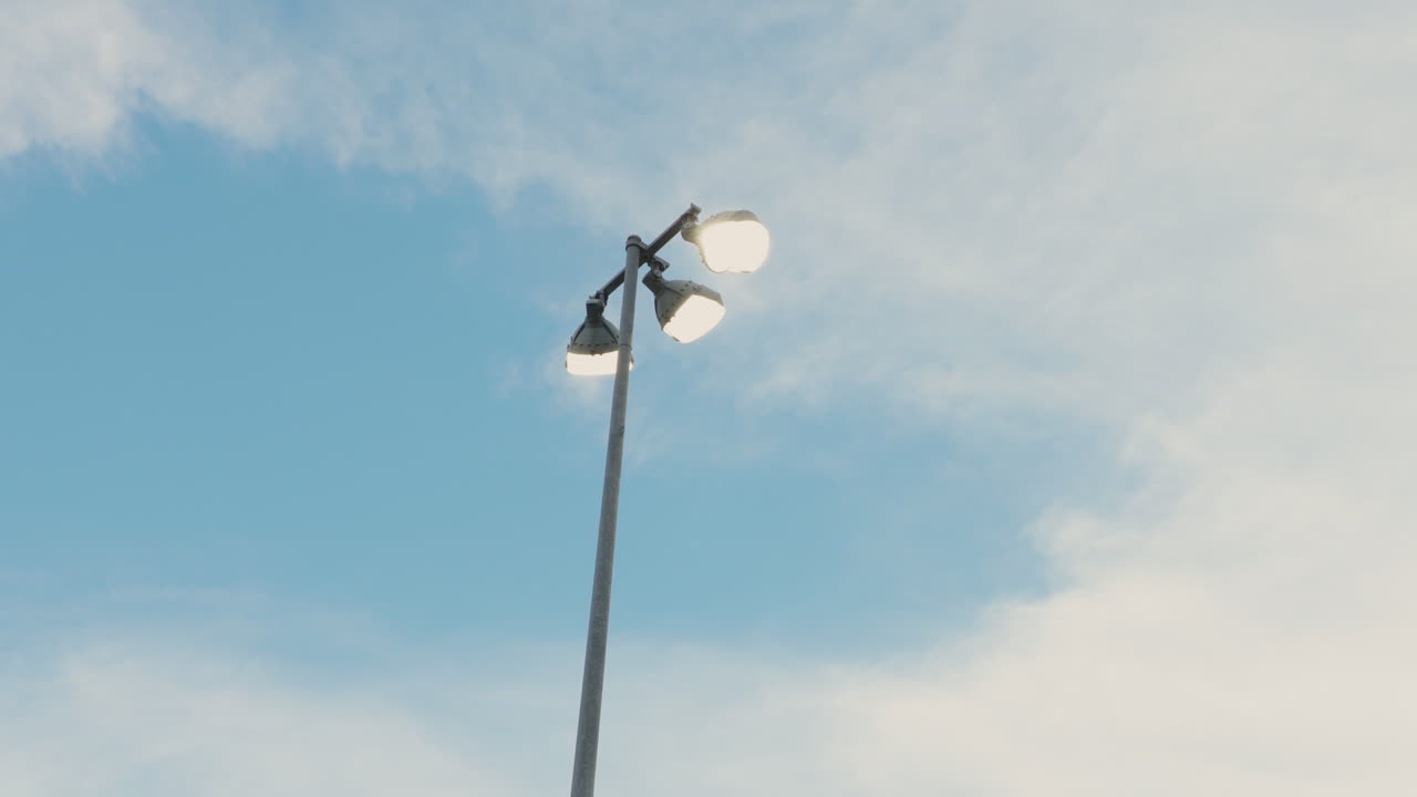A shot of ball field lights against a bright daytime sky, showcasing their towering presence and the clear blue backdrop. The scene captures the essence of sports and outdoor activity.