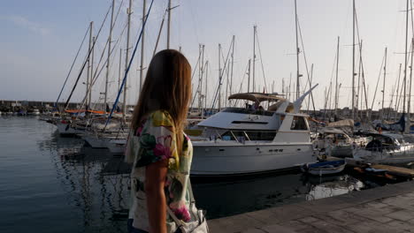 sliding gimbal shot of young woman walking on marina in canary islands