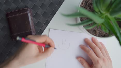 man drawing a smiley face on a paper