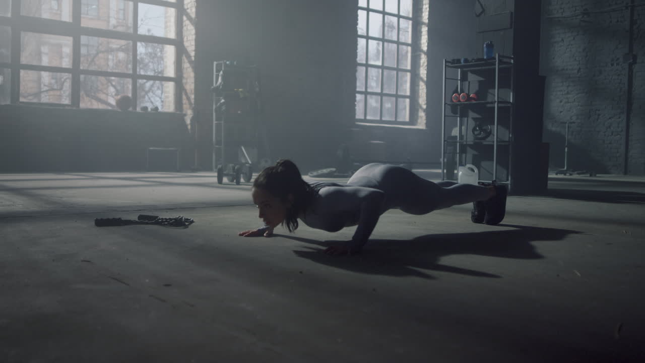 Atleta che fa flessioni in palestra. Donna che si allena in un edificio loft.