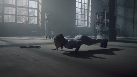 Athlete-doing-push-ups-in-gym.-Woman-making-fitness-training-in-loft-building