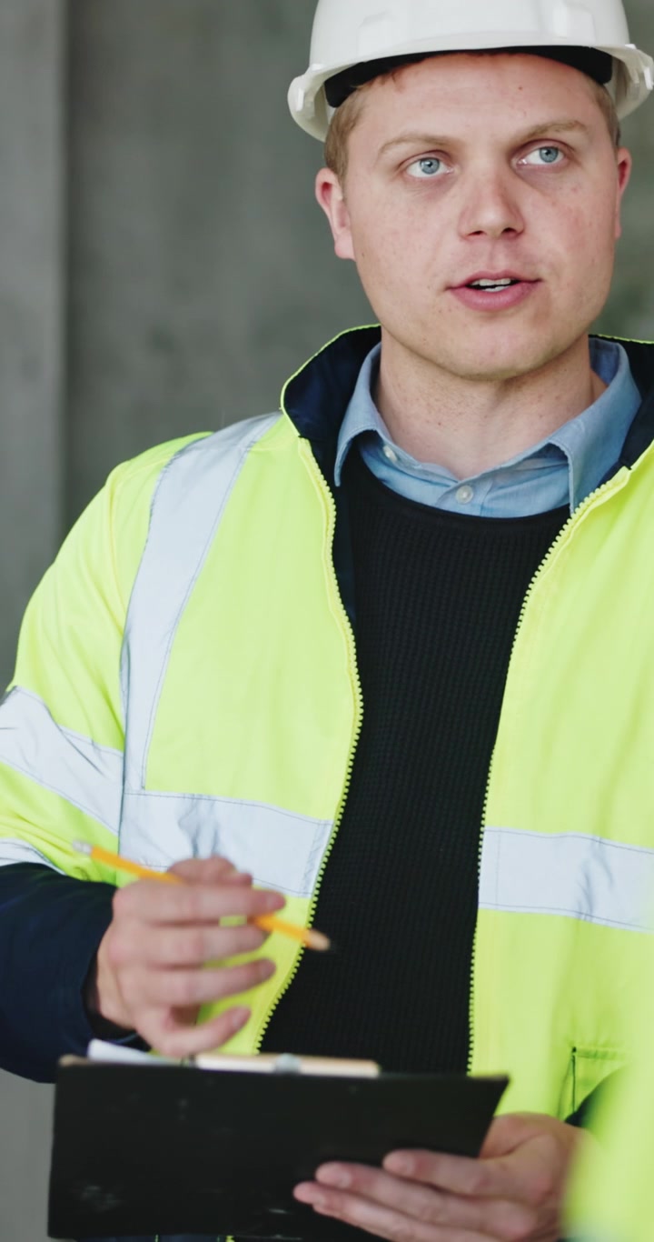 Construction Site Manager Reviewing Plans on Clipboard