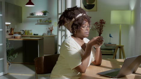 black woman working on laptop in evening at home