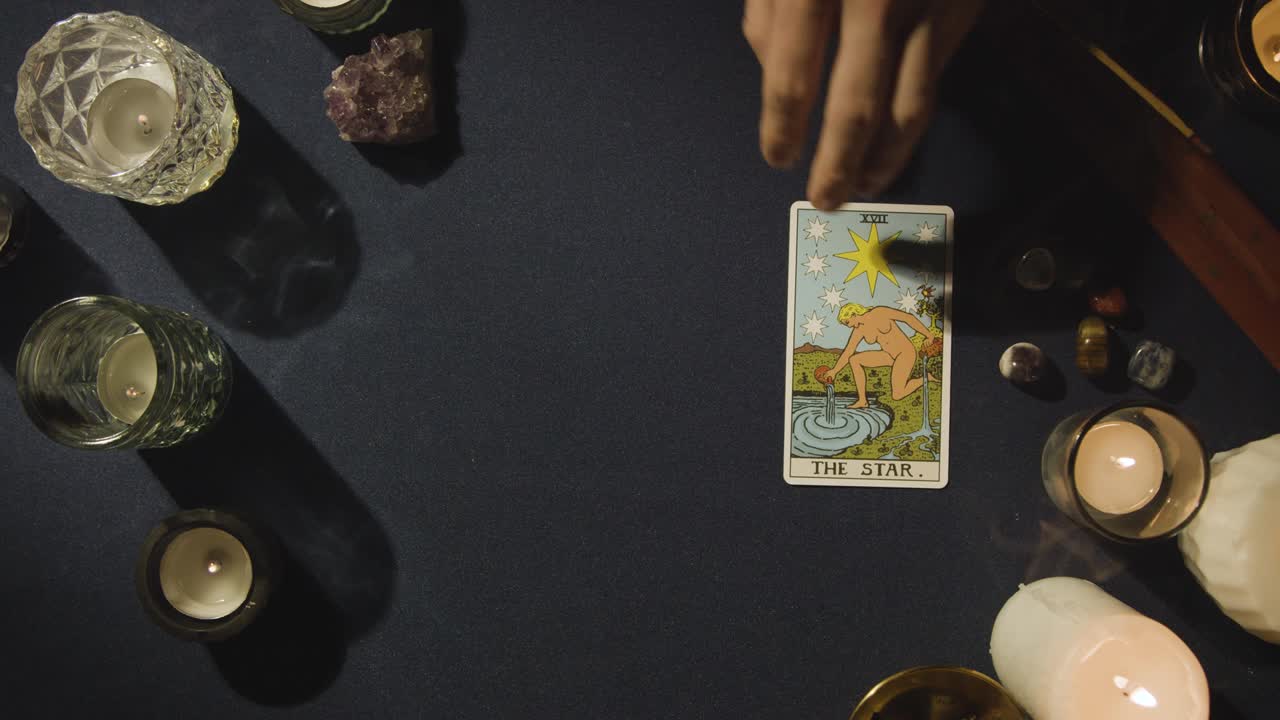 toma aérea de una persona que da lectura de cartas del tarot colocando la carta de la estrella en la mesa