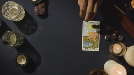 overhead shot of person giving tarot card reading laying down the star card on table