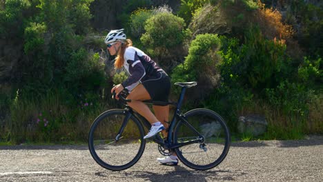 Female-cyclist-starting-cycling-on-a-countryside-road-4k