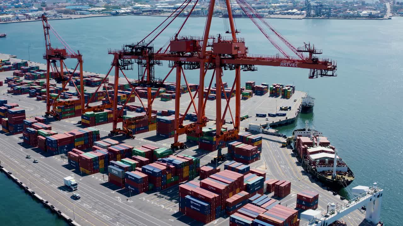 Aerial view of a bustling port with colorful shipping containers and cranes