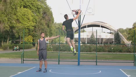 two men playing basketball outdoors in a park