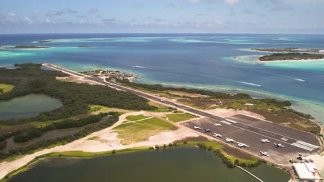 Pista-De-Aterrizaje-De-Los-Roques-Con-Aviones-Estacionados-Y-Mar-Turquesa,-Vista-Aérea