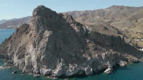 huge rocky cliff stretching into the blue water of lentas southern crete greece drone track in 4k 60fps