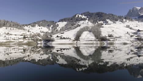 vuelo contra la orilla de un lago reflectante en los alpes suizos