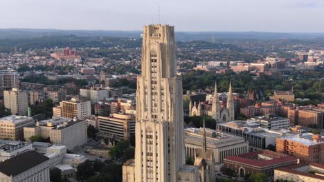 a cinematic orbiting aerial establishing shot of pitt campus' cathedral of learning in pittsburgh's oakland district in late summer