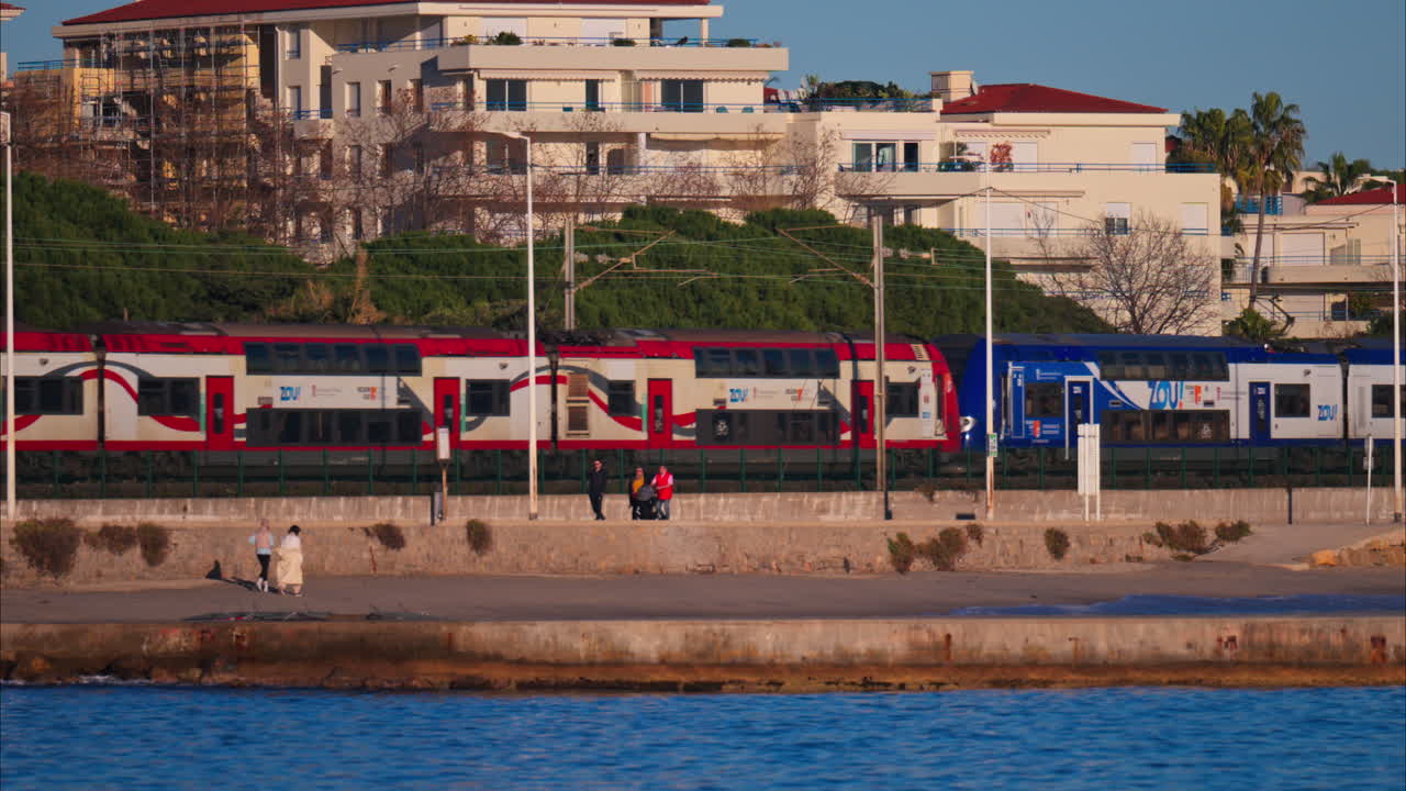 Juan-les-Pins, France - January 25, 2025: Red train moving on the rails in Antibes, on the coast of the sea