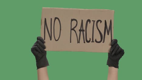 female hands in black gloves pick up a poster from a cardboard box that reads no racism. the concept of the global problem of racism in the world. green screen, chroma key. close up. slow motion