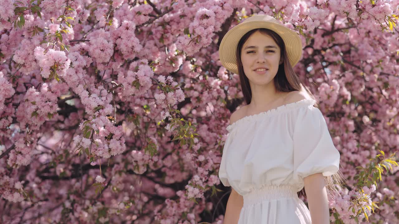 Woman in a white dress among cherry blossoms