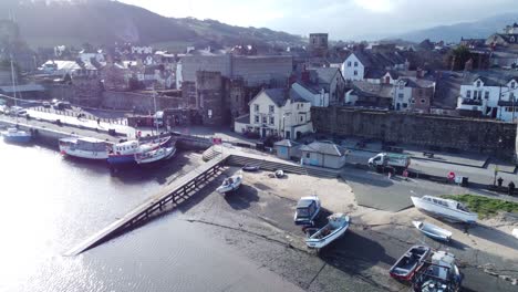 picturesque conwy castle and welsh harbour fishing town boats on coastal waterfront aerial dolly left