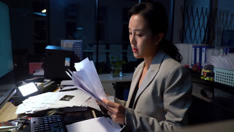 young businesswoman feeling overwhelmed by a mountain of paperwork. she is feeling stressed and frustrated as she looks at her computer screen