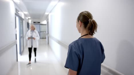 doctoras caucásicas felices saludándose en el pasillo del hospital, cámara lenta